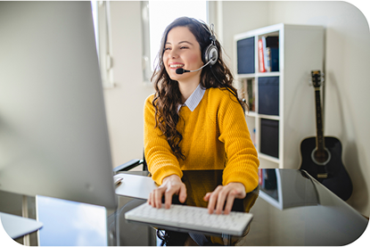 A woman smiling at her desk with a headset on